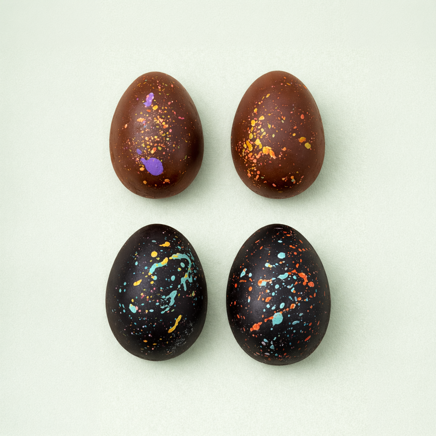 Milk and dark chocolate Easter eggs with colorful splashes