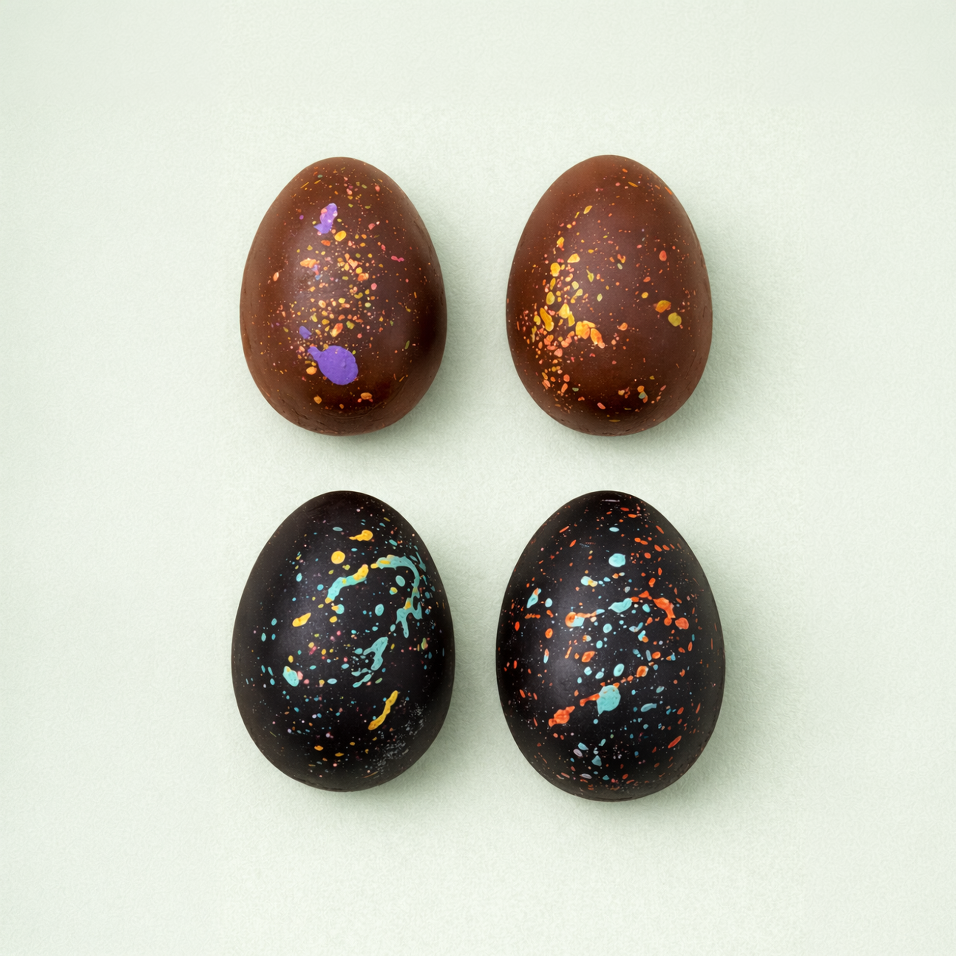 Milk and dark chocolate Easter eggs with colorful splashes